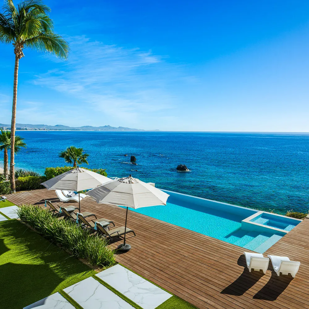 An oceanfront Los Cabos villa with an infinity pool and deck on the edge of the Sea of Cortez, framed by palms