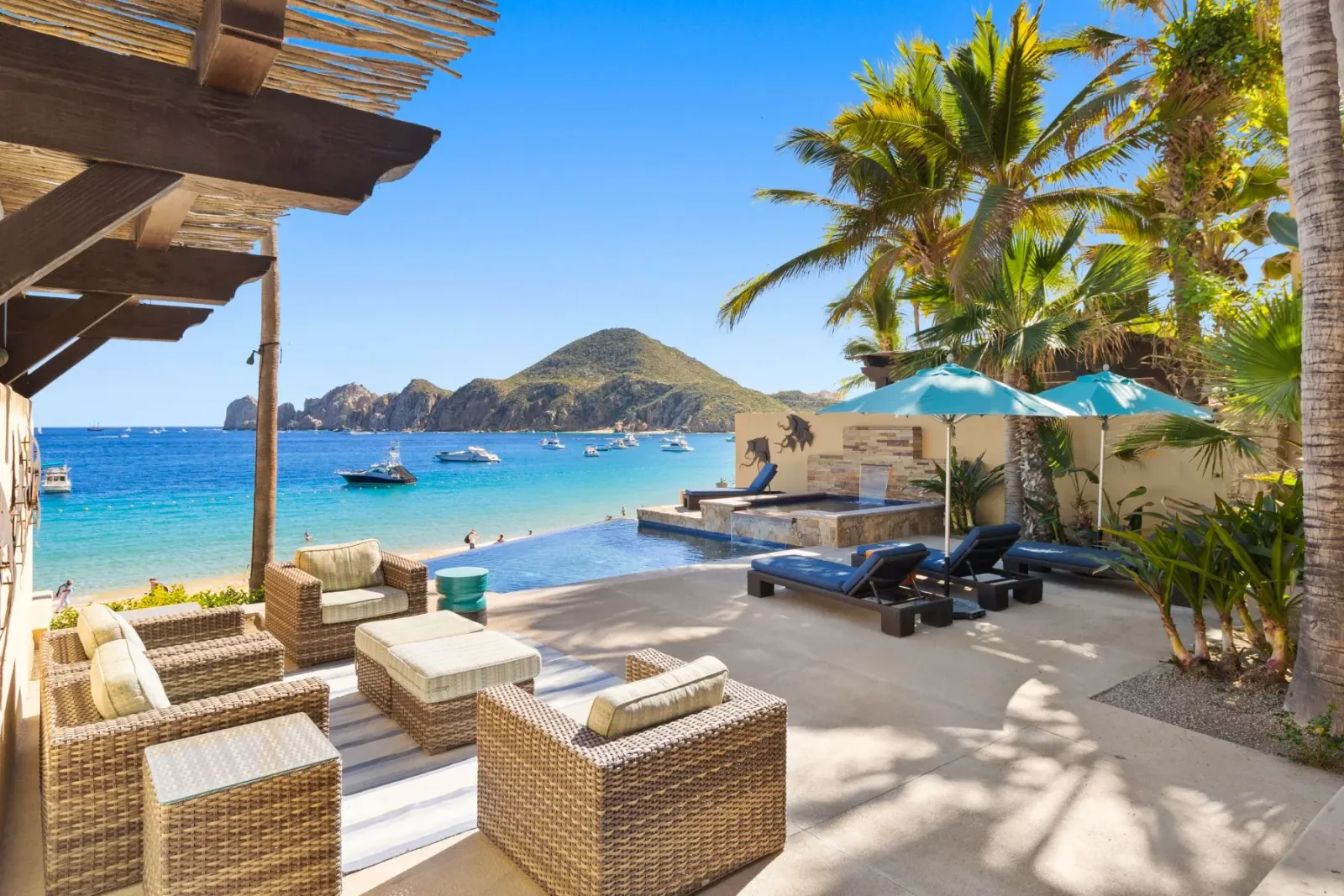 A beachfront villa terrace in Los Cabos overlooking Médano Beach, yachts in the bay, and the Land's End headland