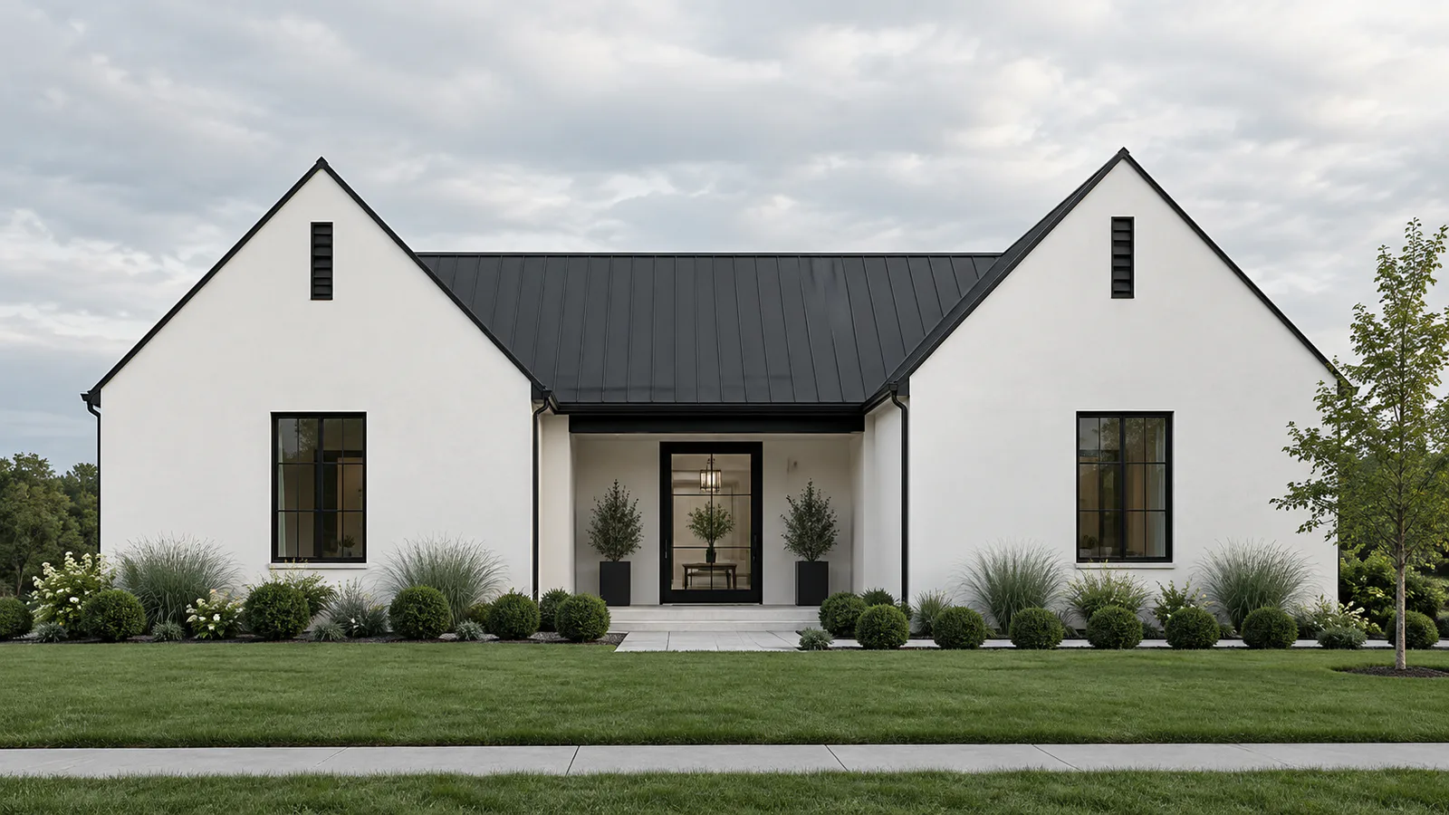 White gabled home with a dark roof and landscaped garden