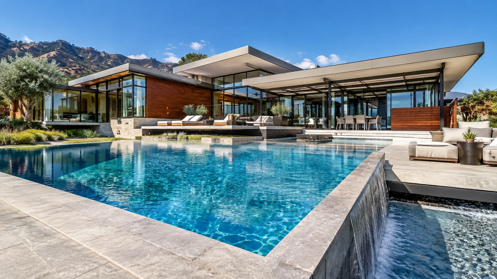 Sunlit modern residence and blue pool against a dry mountain landscape
